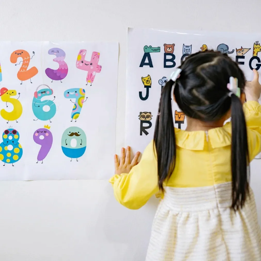 A child pointing at numbers on a classroom wall
