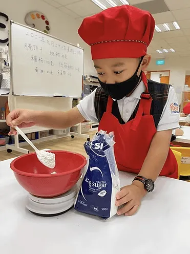 A child in a chef’s hat weighing flour