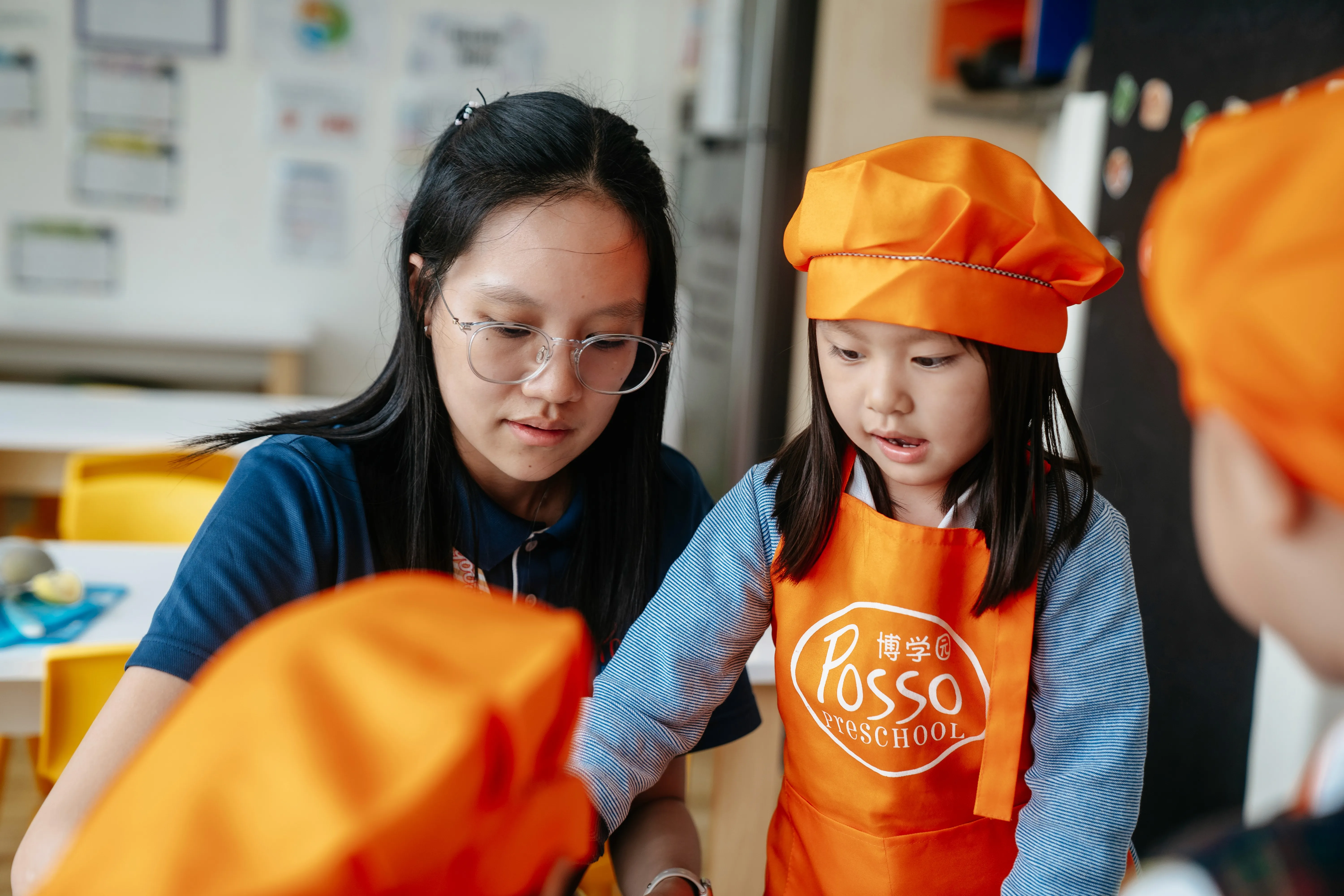 Teacher helping a child in a Posso apron