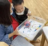 An infant educarer painting with a toddler