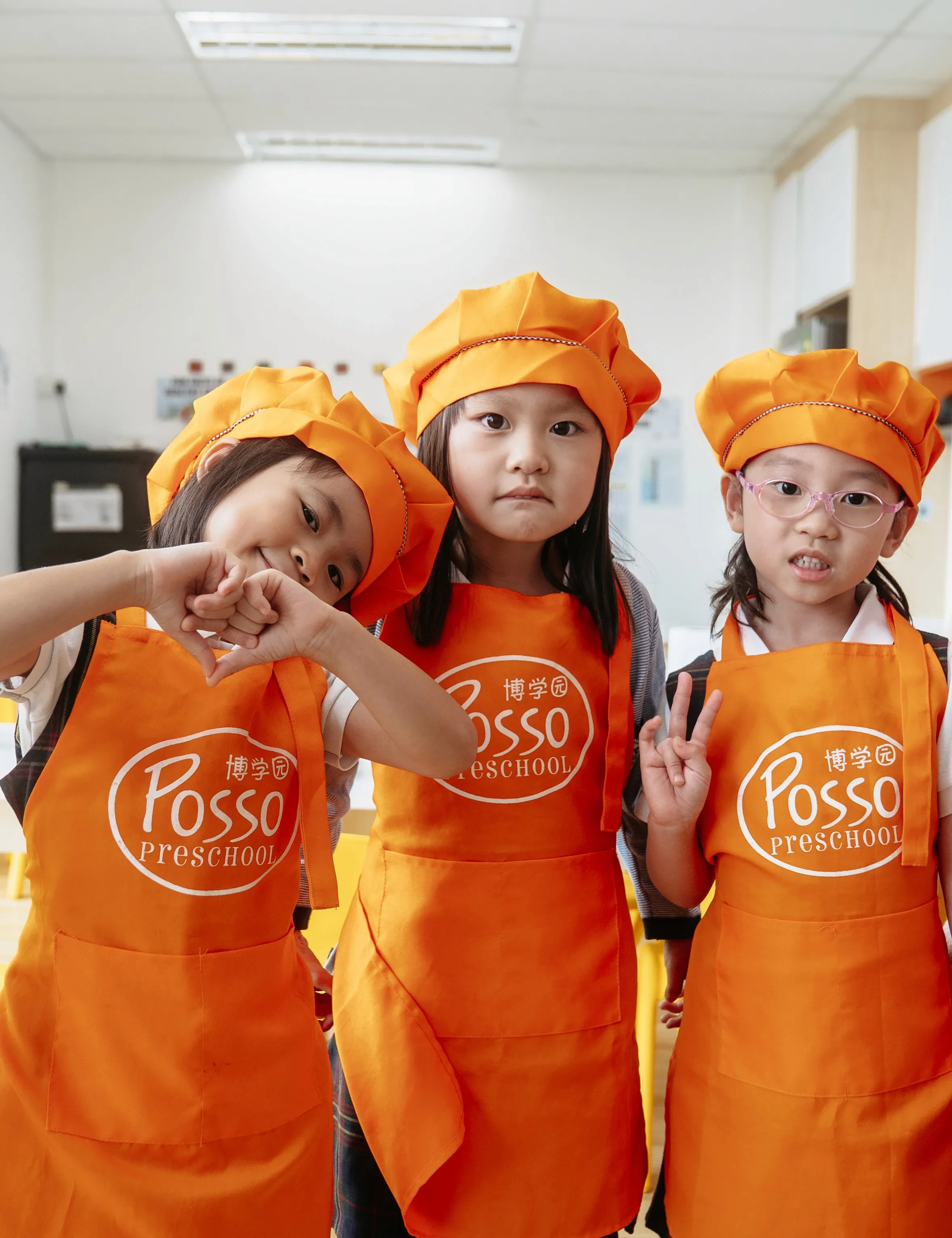 Posso children in orange chef hats and aprons