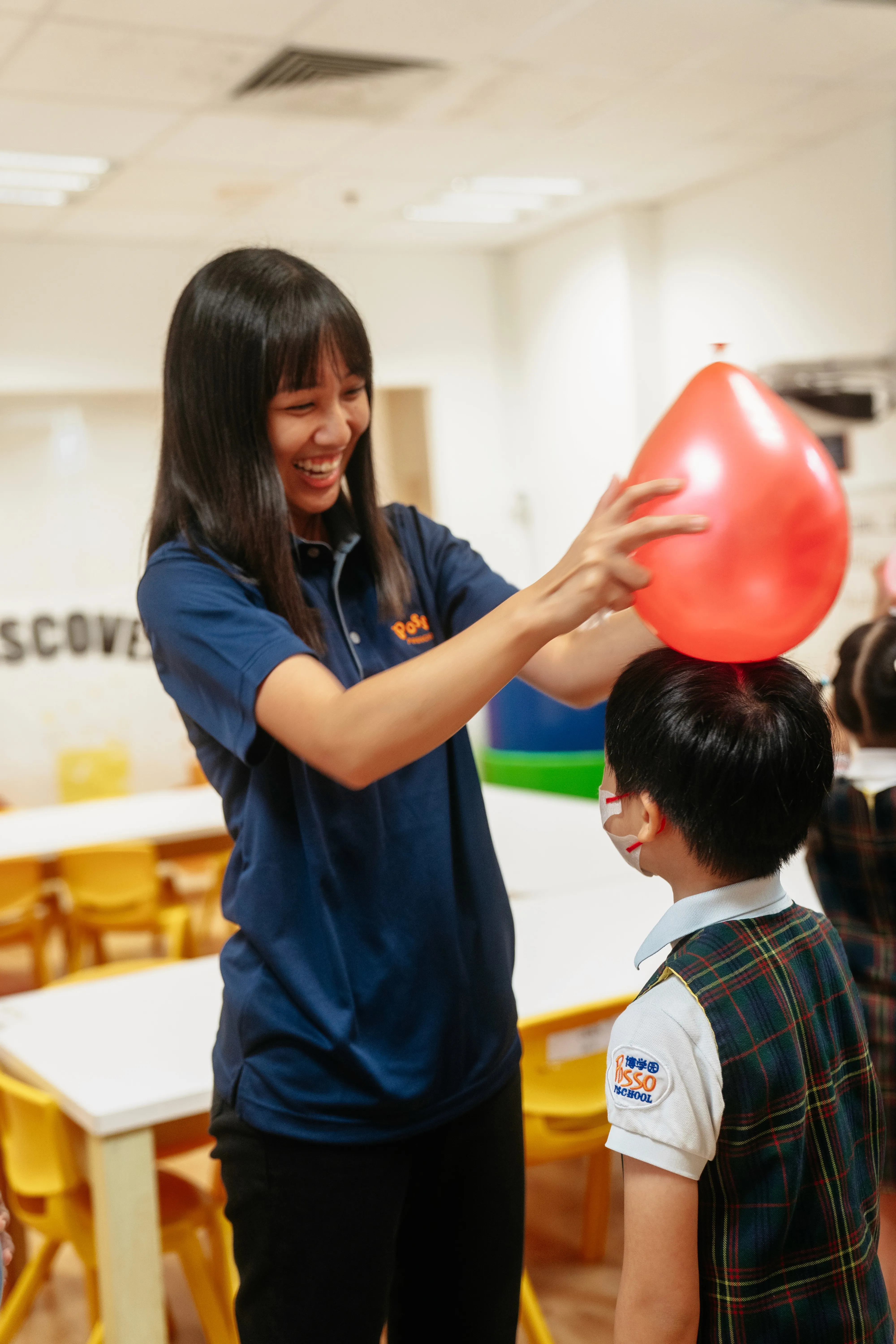 Teacher balancing a balloon on a child’s head