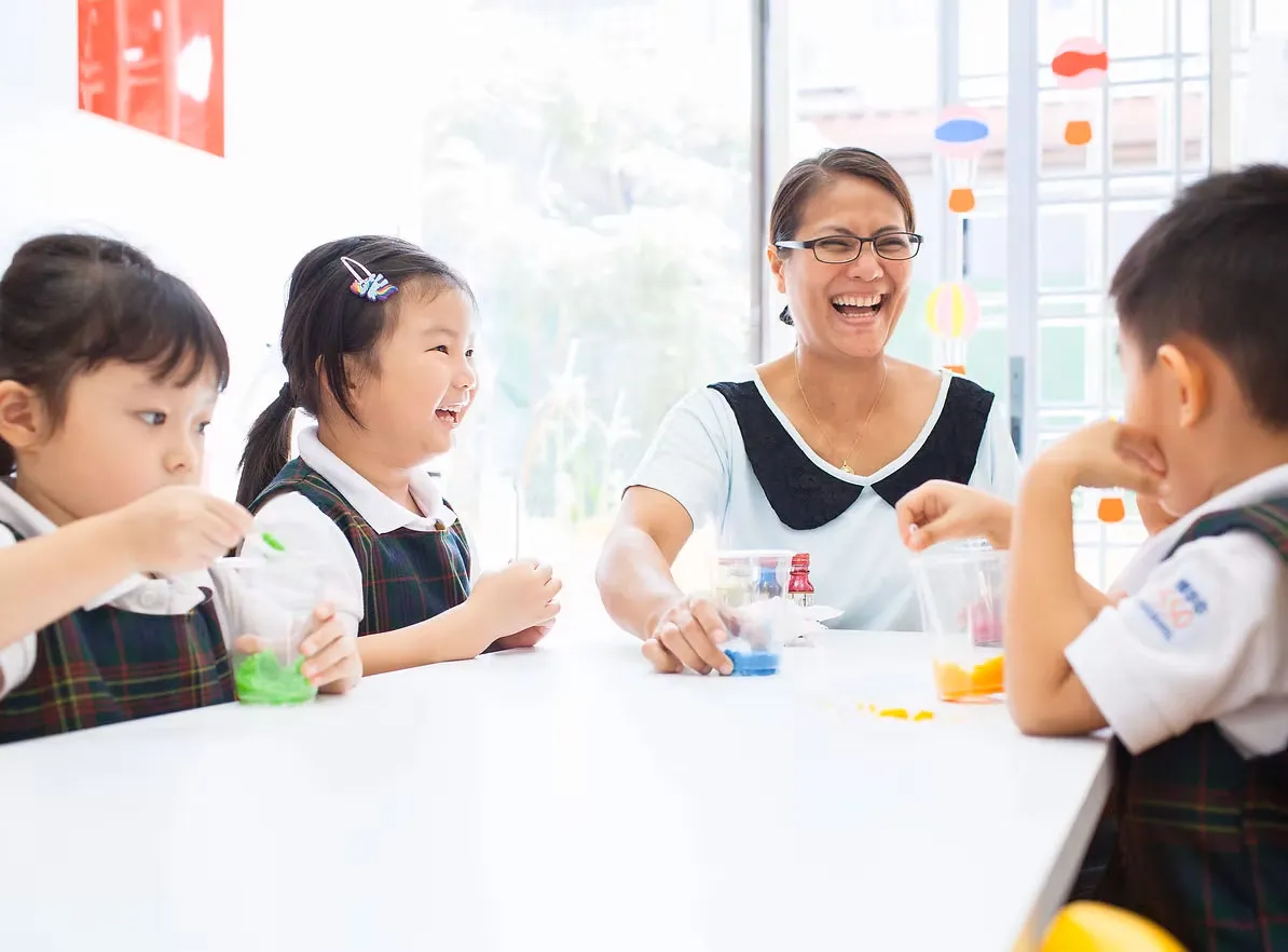 A Posso teacher laughing with children at the table