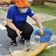An assistant teacher helping with a water play activity