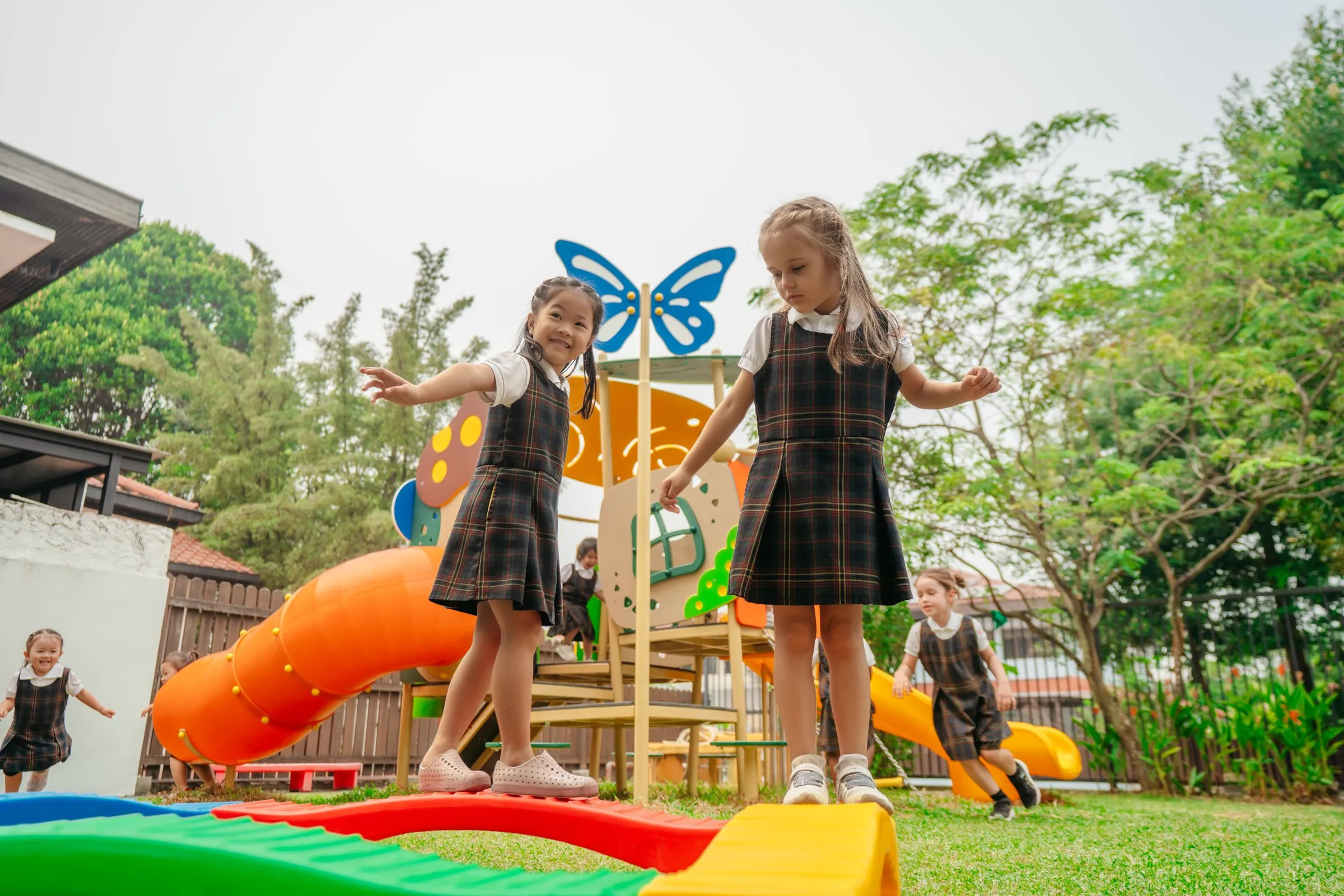 Children balancing on a rainbow beam in the garden playground at Posso West Coast Rise