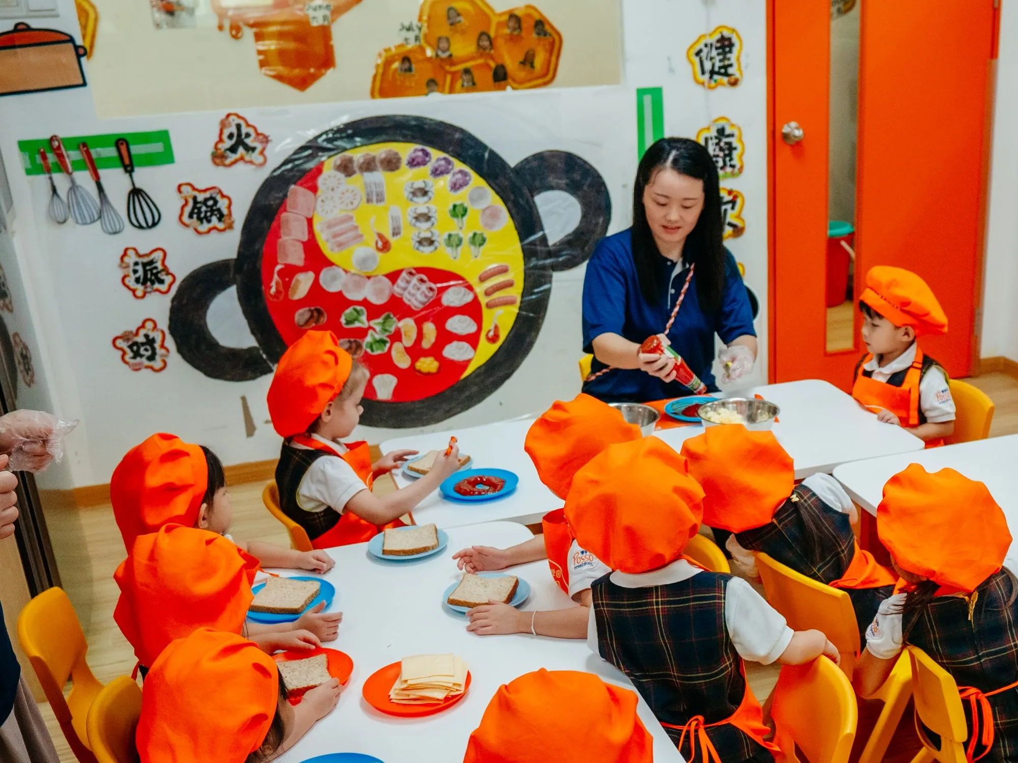 A Posso teacher leading a class, with Chinese characters on the wall behind her